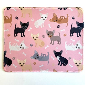 May include: Pink mouse pad with a repeating pattern of cartoon chihuahua dogs in various poses. The dogs are in shades of brown, black, white, and gray.