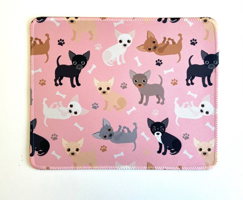 May include: Pink mouse pad with a repeating pattern of cartoon chihuahua dogs in various poses. The dogs are in shades of brown, black, white, and gray.