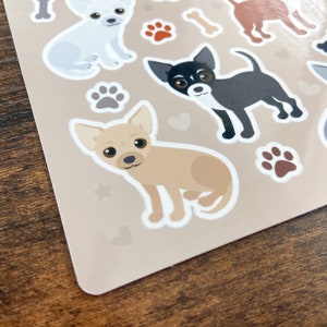 Pu&ograve; includere: Un foglio di adesivi con diversi cani chihuahua di cartoni animati in diverse pose. Gli adesivi sono su uno sfondo beige con impronte di zampe e cuori.