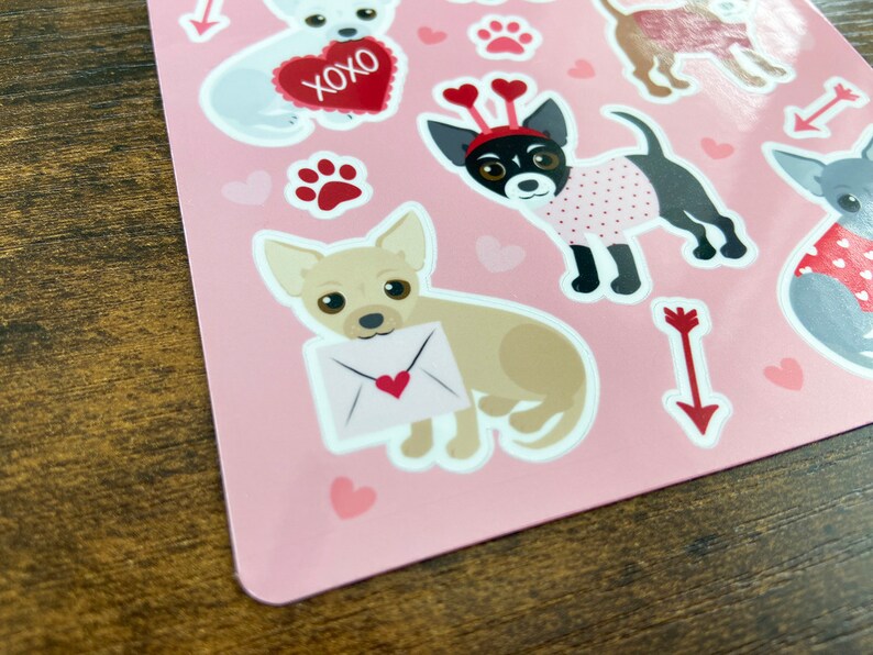 K&ouml;nnte beinhalten: Rosa Blatt mit Aufklebern, die verschiedene Illustrationen von Chihuahuas in verschiedenen Posen zeigen. Einige Aufkleber haben Herzen, Pfotenabdr&uuml;cke und Pfeile. Ein Aufkleber hat den Text "XOXO".