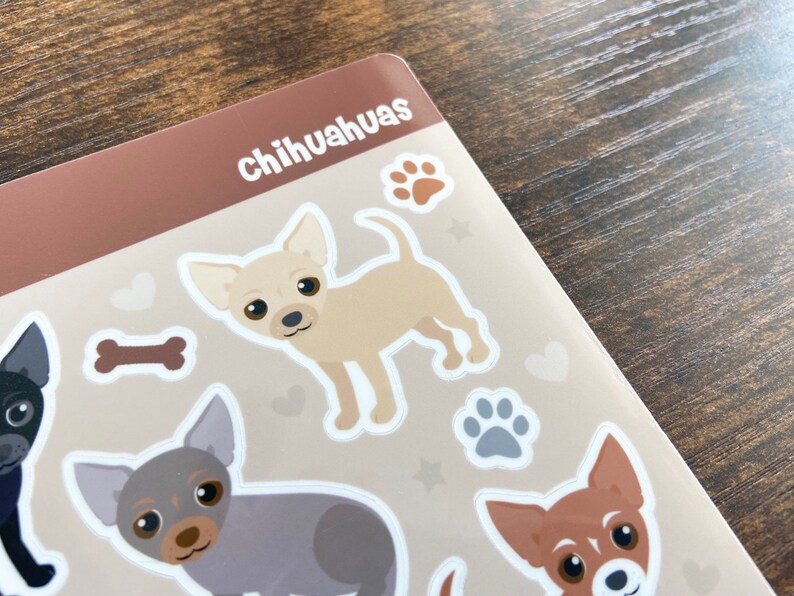 Pu&ograve; includere: Un foglio di adesivi con varie illustrazioni di Chihuahua in diverse pose. Gli adesivi sono su uno sfondo marrone con contorni bianchi. Il testo "Chihuahuas" &egrave; stampato in bianco nella parte superiore del foglio.