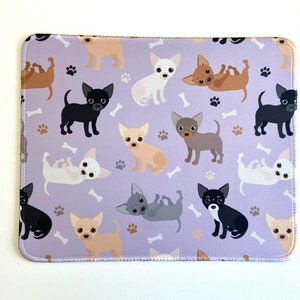 May include: A purple mouse pad with a repeating pattern of cartoon chihuahua dogs in various colors and poses. The dogs are on a light purple background with white paw prints.