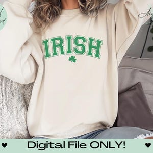 Może przedstawiać: Kremowa bluza z napisem "IRISH" w zielonych literach i zieloną koniczyną pod spodem.