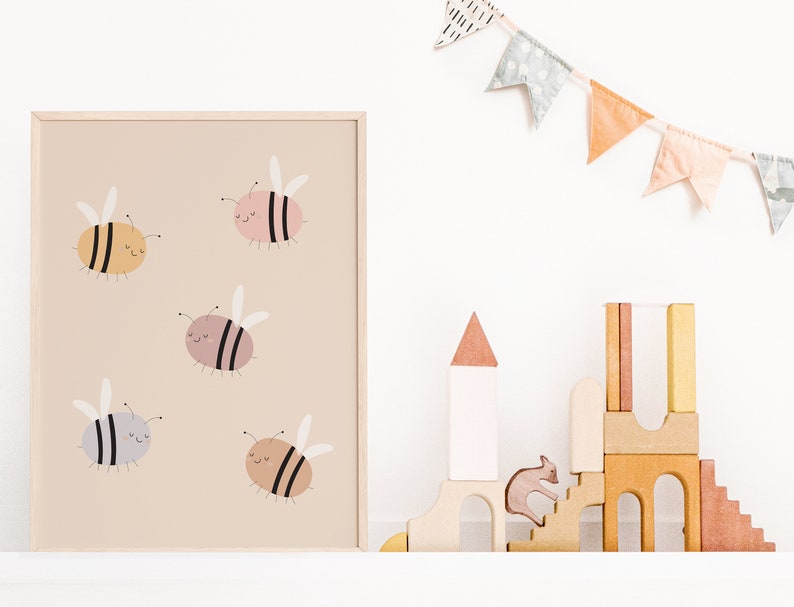 Puede incluir: Una impresi&oacute;n enmarcada con un fondo beige que presenta cinco abejas de dibujos animados en varios colores, incluyendo amarillo, rosa, gris y marr&oacute;n. Las abejas tienen rayas negras y caras sonrientes. La impresi&oacute;n se muestra en un estante blanco con un castillo de juguete de madera y una pancarta de tela.