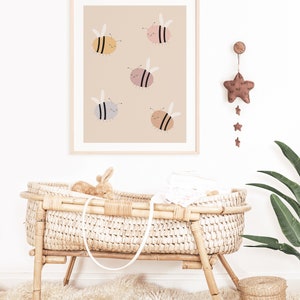 Puede incluir: Una impresi&oacute;n enmarcada con un fondo beige que presenta cinco abejas de dibujos animados en varios colores pastel. Las abejas tienen ojos negros y caras sonrientes. La impresi&oacute;n est&aacute; colgada en una pared blanca.