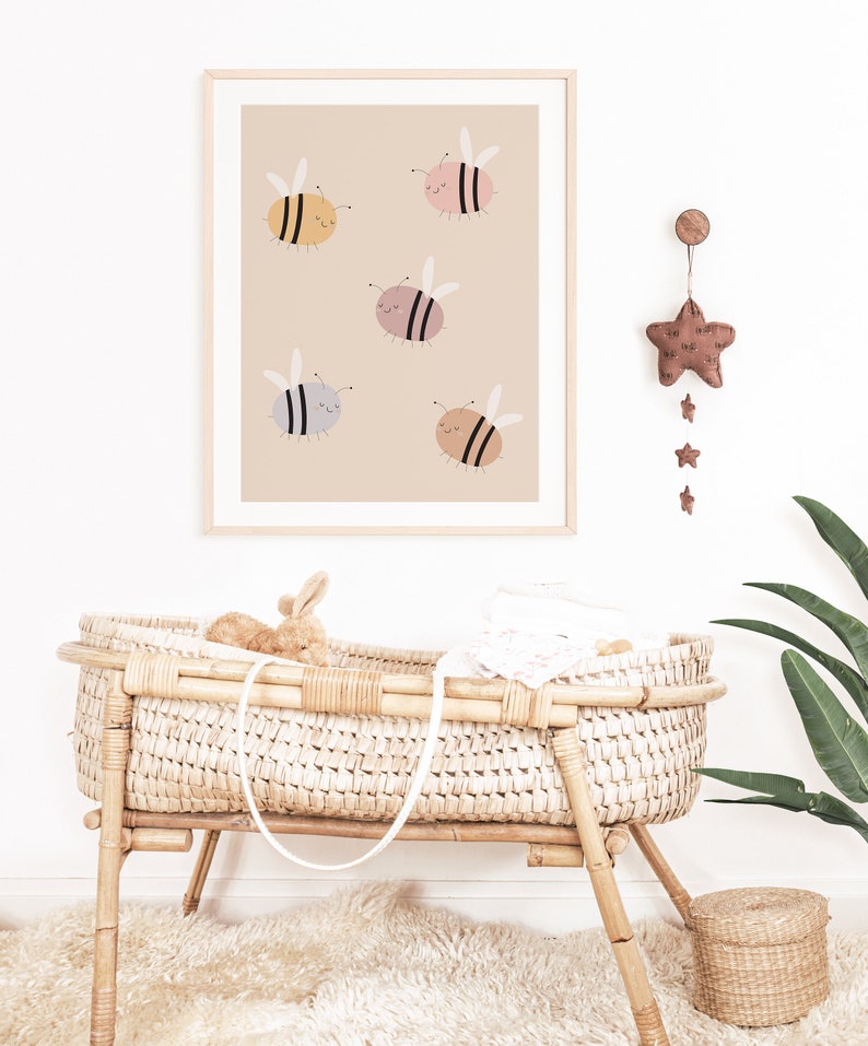 Puede incluir: Una impresi&oacute;n enmarcada con un fondo beige que presenta cinco abejas de dibujos animados en varios colores pastel. Las abejas tienen ojos negros y caras sonrientes. La impresi&oacute;n est&aacute; colgada en una pared blanca.