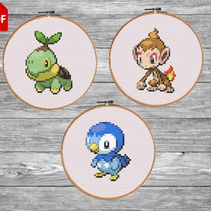 May include: Three embroidery hoops with cross-stitch patterns of Pokemon characters. The first hoop features a green turtle with a leafy head, the second hoop features a brown monkey with a flame tail, and the third hoop features a blue penguin with a white belly.