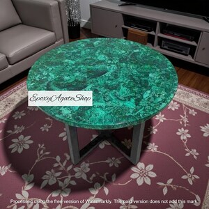 May include: A circular coffee table featuring a striking green malachite surface. The table has a distinctive pattern and is supported by a dark grey metal base. The table is approximately 91 cm in diameter. The text "Epoxy Agate Shop" is visible on the table.