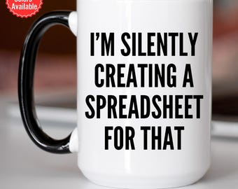 May include: White ceramic coffee mug with a black handle and rim. The mug has black text that reads "I'm silently creating a spreadsheet for that."