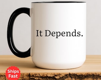 May include: White ceramic mug with a black handle and rim. The mug features the phrase "It Depends." in black text. The mug is on a wooden surface.