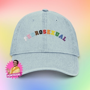 May include: Light blue denim baseball cap with the embroidered word "PEDROSEXUAL" in rainbow colors. The cap features a curved brim and an adjustable strap. A cartoon image of a man is on the side.