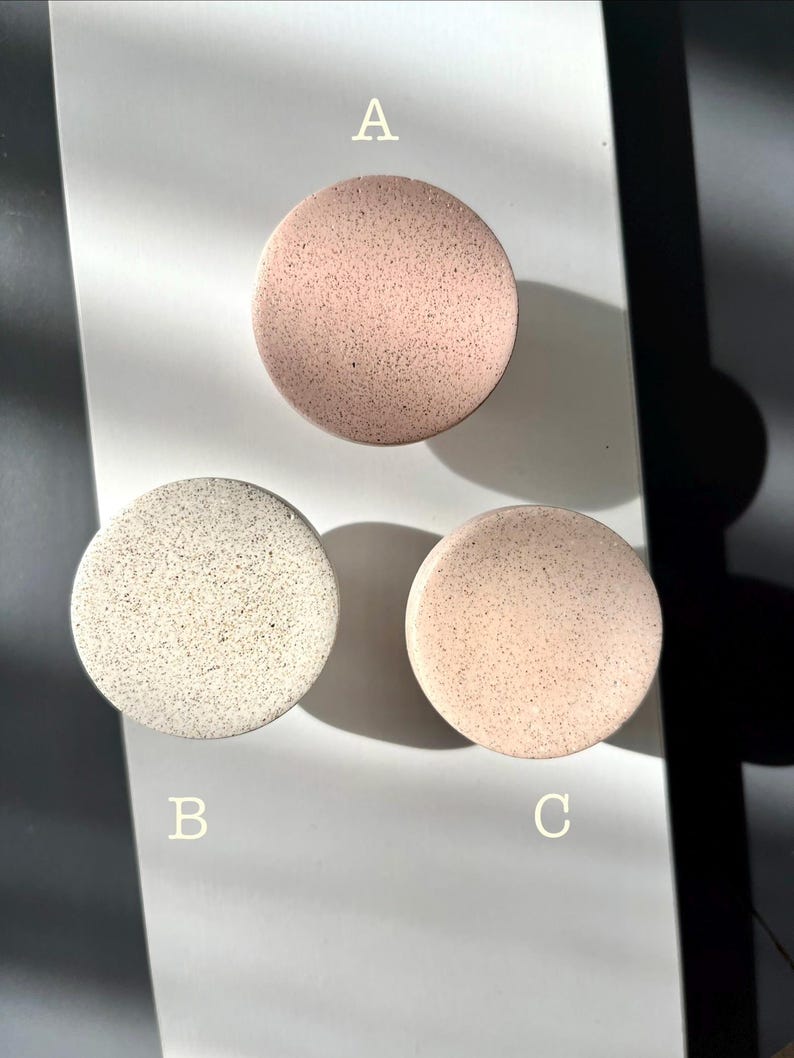 Puede incluir: Tres posavasos redondos y moteados en tonos rosa y blanco roto est&aacute;n dispuestos sobre una superficie blanca. Los posavasos est&aacute;n etiquetados A, B y C. Los posavasos tienen un aspecto texturizado.