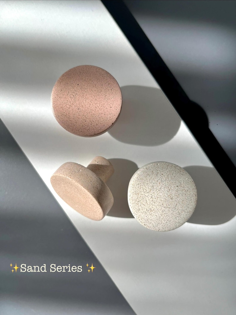 Puede incluir: Tres piezas de cer&aacute;mica en tonos neutros. Dos son redondas y una tiene un asa. El texto "Sand Series" se encuentra en la parte inferior izquierda de la imagen.