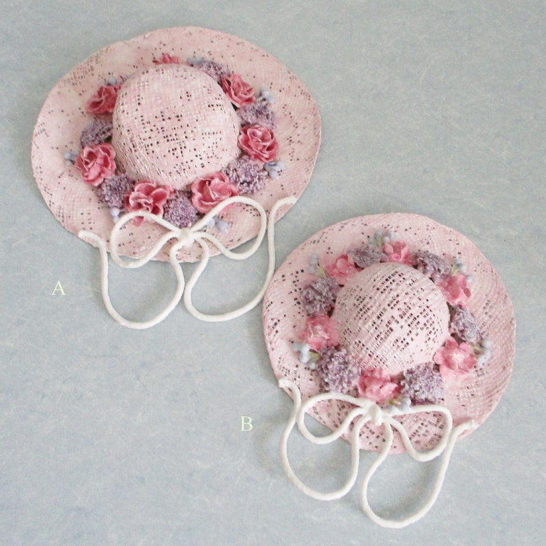 May include: Two pink straw hats with white ribbon ties and pink and purple flower embellishments. The hats are labeled A and B.