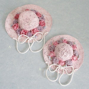 May include: Two pink straw hats with white ribbon ties and pink and purple flower embellishments. The hats are labeled A and B.