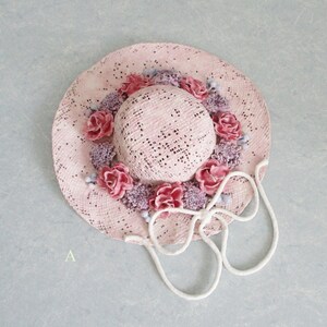 May include: A pink straw hat with a white ribbon and pink and purple flowers around the crown.