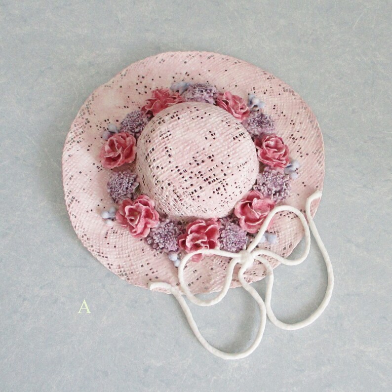 May include: A pink straw hat with a white ribbon and pink and purple flowers around the crown.
