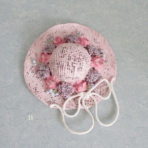 May include: A pink straw hat with a white ribbon and pink and purple flowers around the crown.