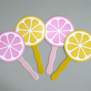 May include: Four paper hand fans with yellow and pink lemon designs. The fans have white handles.