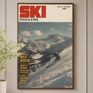 Peut inclure: Une affiche murale encadrée de la couverture du magazine Ski de décembre 1984 montrant un skieur sur une pente enneigée. Le texte indique SKI MAGAZINE, ISSUE 51 - DECEMBER 1984, THE WILD WINTER, BANFF & BEYOND, CANADA'S BEST BACKCOUNTRY, TESTED: SKIS, BOOTS & GOGGLES FOR '85.