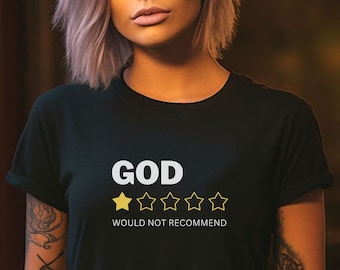 May include: Black t-shirt with the text "GOD" above a one-star rating and the words "WOULD NOT RECOMMEND". The model is wearing black jeans and has tattoos on both arms.