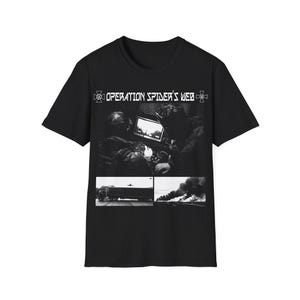 Könnte beinhalten: Schwarzes T-Shirt mit dem Text "OPERATION SPIDER'S WEB" über einem Graustufenbild. Das Bild zeigt zwei Personen, die auf einen Bildschirm schauen, und zwei kleinere Bilder darunter, eines von einem Lastwagen und eines von einem Feuer.