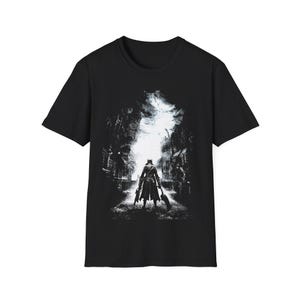 May include: Black t-shirt featuring a detailed grayscale graphic of a figure in a long coat, holding weapons, standing in a dark, gothic-style street. The design has a dramatic, shadowy aesthetic, with a bright light source in the background.
