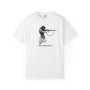 May include: White t-shirt featuring a black and white illustration of a person aiming a rifle. The text "Tiocfaidh ár lá" is printed below the image. The shirt has a crew neck and short sleeves.