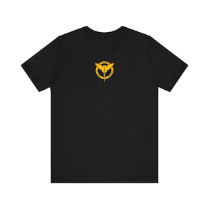 May include: Black t-shirt with a gold graphic of a winged symbol with a sword and the text "FORGED IN FIRE" around it.