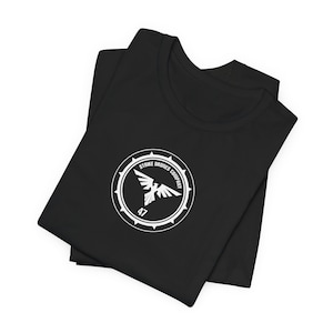 May include: Black t-shirt with a white logo featuring a bird in a circle with the text "Strike Drones Company 47".