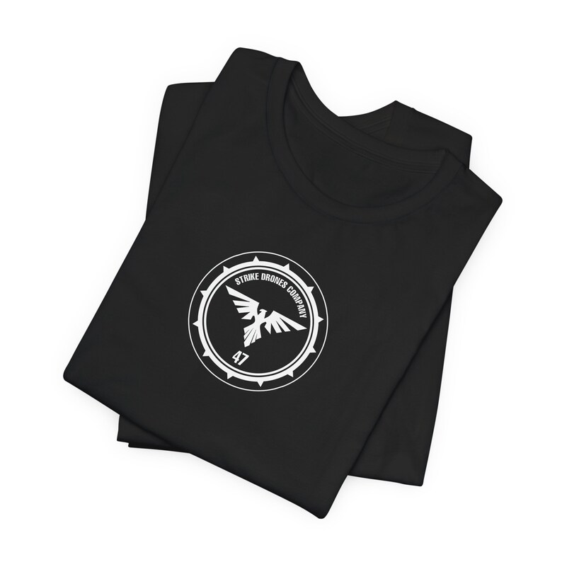May include: Black t-shirt with a white logo featuring a bird in a circle with the text "Strike Drones Company 47".