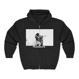Peut inclure: Sweat à capuche zippé noir avec un motif en noir et blanc d'une personne visant avec un fusil. Le motif est placé sur un fond rectangulaire blanc. Le texte "Tiocfaidh ár lá" est imprimé en blanc en dessous.