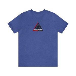 May include: Blue t-shirt featuring a black, red, and white Kraken logo. The logo is a triangle with the word "KRAKEN". The shirt is made of a soft material.