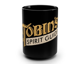 Może przedstawiać: Czarny kubek ceramiczny z złotym wzorem, na którym widnieje napis "Tobin's Spirit Guide".