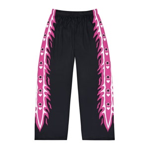 Może przedstawiać: Czarne spodnie z różowym i białym wzorem płomieni po bokach. Płomienie mają białe gwiazdki i różowe serduszka wzdłuż krawędzi.