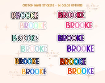 May include: A set of 14 colorful name stickers with the name "BROOKE" in different color combinations. The stickers are arranged in two columns of seven stickers each.