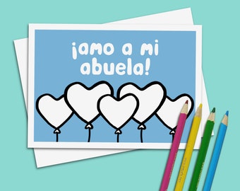 May include: A greeting card with a light blue background and the text "¡Amo a mi abuela!" in white. The card features five white heart-shaped balloons with black outlines. Colored pencils in pink, yellow, green, and blue are in the foreground.