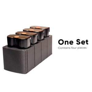 Puede incluir: Un juego de cuatro cartuchos de tinta negros en un soporte de plástico negro. El texto "One Set Contains four pieces" es visible debajo de los cartuchos.