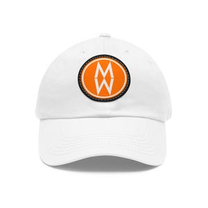 Op de afbeelding: Witte baseballpet met een gebogen klep. De pet heeft een oranje ovale patch met een zwarte rand en een witte gestikte omtrek. Binnen de ovaal is een witte gestileerde letter "M" en "W".