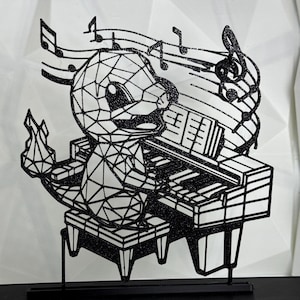 May include: Black and white laser-cut art piece depicting a polygonal creature playing a piano. Musical notes float above the piano. The art piece is mounted on a black base, with a white geometric background.