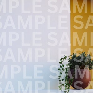 May include: A potted plant with green leaves sits on a white surface against a wall with a yellow accent. The wall is covered in a repeating pattern of the word "SAMPLE".