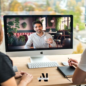 May include: Two people are having a video call on a computer. The person on the screen is sitting in a restaurant and holding a glass of water. The person on the left is looking at the screen, while the person on the right is looking at the screen and holding a pen.