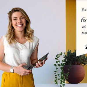 May include: A woman smiles while holding a tablet in front of a white and yellow wall. The wall has a white sign with the text "Easy to use! For Zoom, as overlay and more... Zoomnetic".