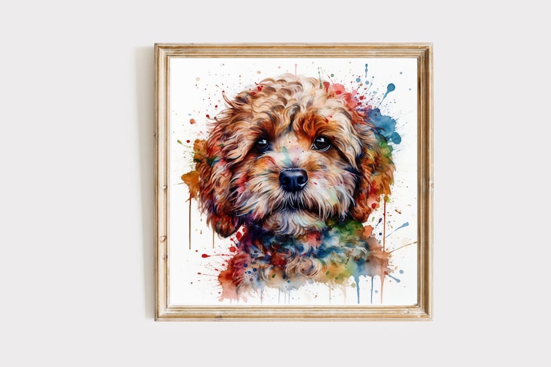 May include: A framed watercolour painting of a Cavapoo dog. The dog's brown fur is contrasted by colourful paint splatters in red, blue, green, and yellow. The artwork is presented on a white background within a wooden frame.