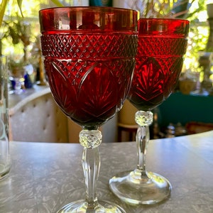 May include: Two red wine glasses with a clear stem and base. The glasses have a diamond pattern and a leaf design.