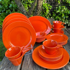 May include: A set of orange vintage dinnerware, including plates, bowls, and cups. The set features a unique grooved design and is perfect for a retro-themed dinner party.