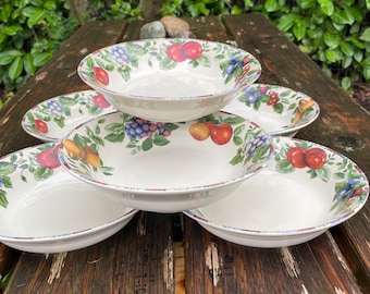 May include: A set of six white ceramic bowls with a fruit and floral design. The bowls are stacked on top of each other, with the largest bowl at the bottom and the smallest bowl at the top.