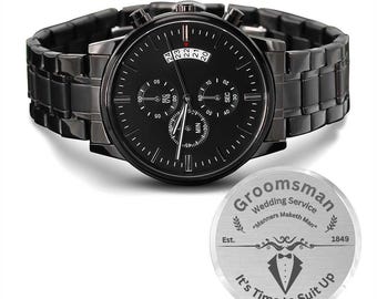 May include: Black chronograph watch with a black band and a silver engraved circular tag that reads "Groomsman Wedding Service "Manners Maketh Man" Est. 1849 It's Time to Suit Up"