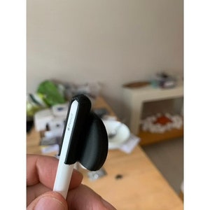 May include: A white stylus with a black silicone grip. The grip has a small, black, round, silicone tip.
