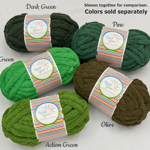 May include: Five skeins of Spirit Yarn in different shades of green. The colors are Dark Green, Pine, Green, Action Green, and Olive. The yarn is a chunky, fuzzy texture. The label on each skein says "Spirit Yarn Show Your Colors!"
